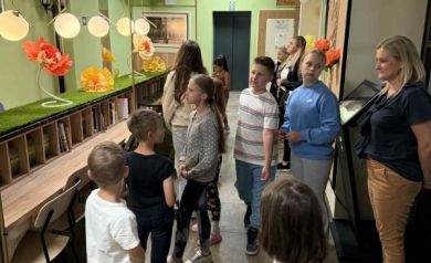 Na fotografii dzieci i jedna kobieta dorosła. Widniej tam również lampy w kształcie kul, kwiaty wykonane z papieru, a także widoczny jest napis Wagon Renarda.