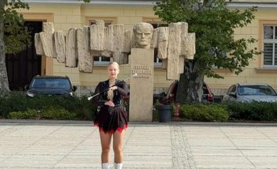 Jedna z mażoretek ubrana w czarno-czerwony strój podczas swojego występu.