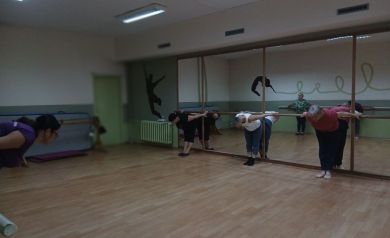 Kobiety przy drążkach wykonują skłon.