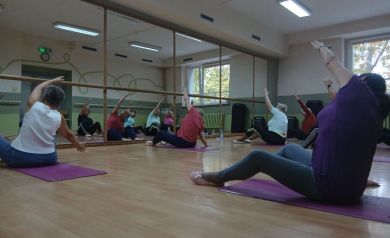 Kobiety wykonujące ćwiczenia rozciągające na matach sportowych.