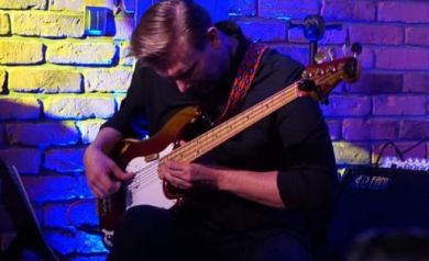 Alan Wykpisz gra na gitarze basowej.