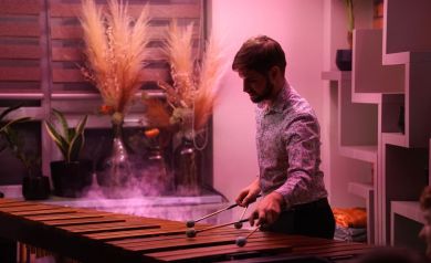 Muzyk grający na marimbie. Artysta otulony jest przydymionym światłem scenicznym w kolorze różu.