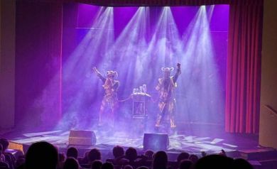 Na pierwszym planie publiczność. Dalej na scenie widać aktorów podczas swojego występu. 