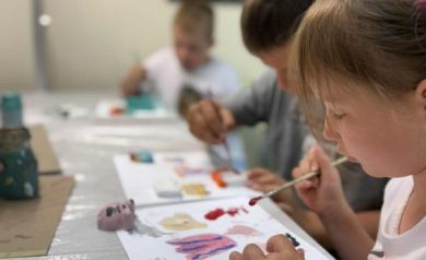 Dzieci z pędzlami w ręku malują farbami obrazki i figurki. 