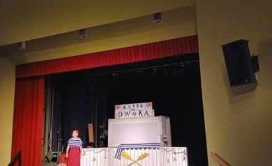 Artystka na scenie podczas występu. Na zdjęciu widnieje również dekoracja ustawiona na scenie. 