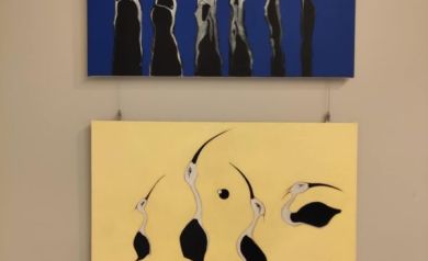 Na zdjęciu dwa obrazy jeden w odcieniach niebieskiego, białego i czarnego koloru, drugi zaś w odcieniach żółtego z namalowanymi ptakami. Obrazy wiszą na ścianie.