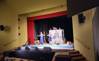 Aktorzy podczas swojego występu. Wokół nich dekoracje. 