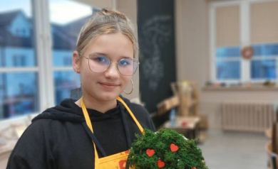 Na zdjęciu dziewczyna w fartuszku prezentująca swoja pracę. 