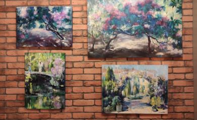 Cztery obrazy wiszące na ceglastej ścianie. Obrazy przedstawiają roślinność. 