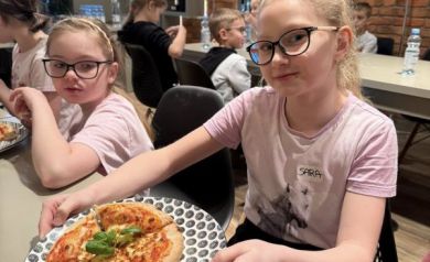 Dziewczynka przedstawia swoją pizzę na talerzu