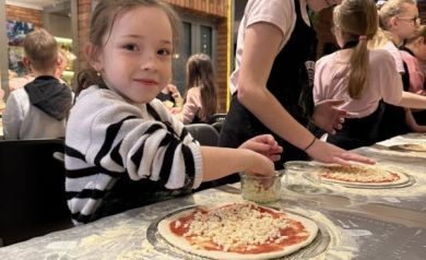 Dziewczynki rozkładają ser na pizzy