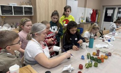 Pani pokazuje dzieciom, w jaki sposób malować kubki