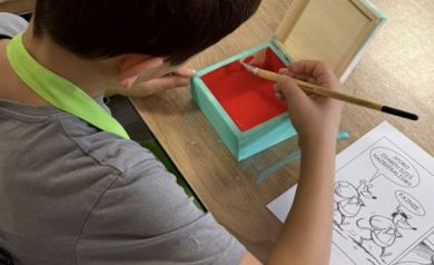 Chłopczyk malujący wnętrze pudełka na czerwono