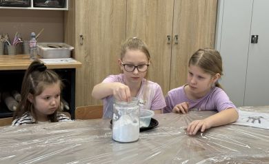 Trzy dziewczynki wsypujące substancję do słoika