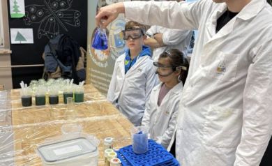 Pan pokazuje dzieciom niebieski płyn w szklanej kolbie