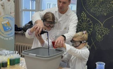 Pan pomaga dziewczynkom wlać czarny płyn do miski