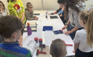 Dzieci oglądają, jak jedna z dziewczynek maluje po swoim linorycie