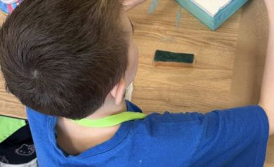 Chłopczyk malujący drewniane pudełko na niebiesko