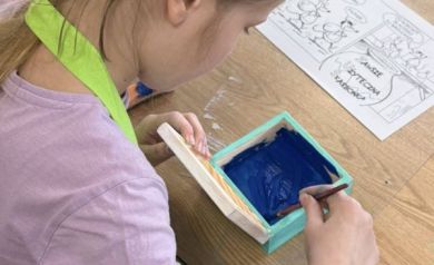 Dziewczyna maluje środek pudełka ciemnoniebieskim kolorem