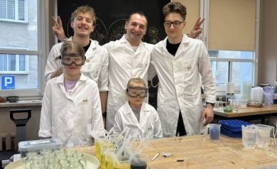 Trzej mężczyźni i dwójka dzieci ubrana w laboratoryjne scrubsy pozuje do zdjęcia