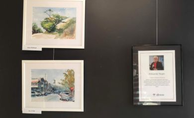 Trzy obrazy artysty powieszone na ciemnej ścianie