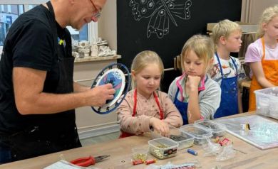 Na zdjęciu dzieci oraz prowadzący warsztaty podczas pracy nad zegarami. 