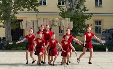 Grupa mażoretek podczas swojego występu. Mają czerwone stroje.