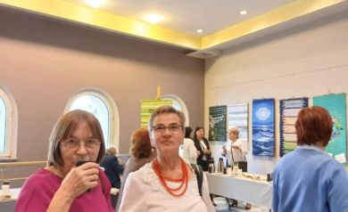 Uczestnicy 5. Strzeleckiego Święta Seniorów na holu Strzeleckiego Ośrodka Kultury podczas poczęstunku. Na pierwszym planie dwie kobiety patrzące w stronę aparatu.