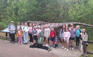 Grupka dzieci na zdjęciu grupowym przy dwóch modelach dinozaurów.