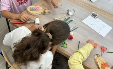 Dzieci siedzące przy stole podczas warsztatów string art. 