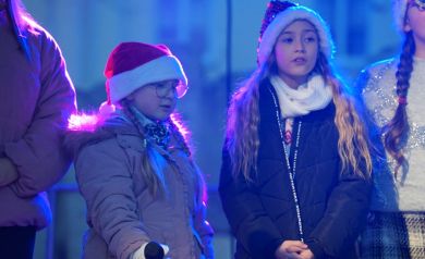 Dzieci w świątecznych czapkach podczas występu na scenie. 