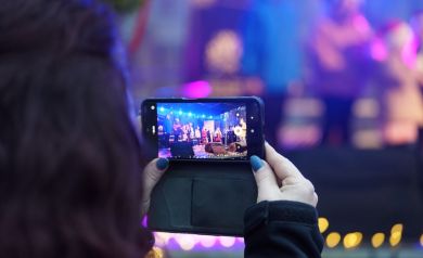 Zdjęcie telefonu nagrywającego występ dzieci na scenie.