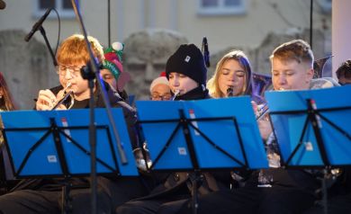 Występ orkiestry dętej. Przed muzykami ustawione są pulpity z niebieskimi teczkami.