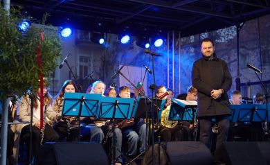 Orkiestra dęta wraz z dyrygentem na scenie. 