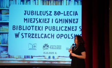 Kobieta przemawiająca do mikrofonu. Widać również prezentację wyświetlaną z projektora. 