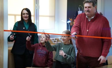 Moment przecinania nożyczkami wstęgi przez kobietę, mężczyznę, chłopca i dziewczynkę.