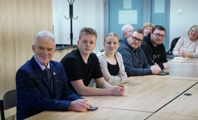 Dorośli i młodzież siedzący przy stolikach.