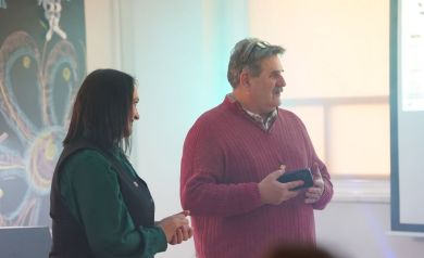 Na zdjęciu kobieta i mężczyzna. Mężczyzna trzyma w dłoni telefon, a na głowie ma założone okulary.