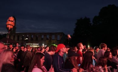 Publiczność ogląda występ oraz macha światłami z telefonów w rytm melodii.