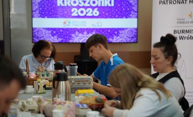 Chłopak pracujący nad kroszonką, w tle skupione trzy kobiety i mężczyzna