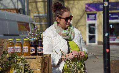 Sprzedawczyni prezentuje soki i syropy ekologiczne własnej produkcji.