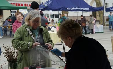 Pani z koła gospodyń wiejskich wydaje kupującej bułkę z wołowiną . 