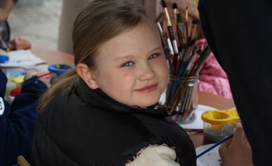 Portret uśmiechniętej dziewczynki, malującej ozdoby wielkanocne.