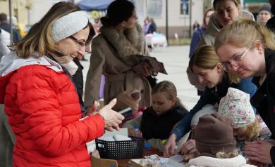 Instruktorka warsztatów plastycznych na jarmarku, pomaga dzieciom przy dekoracji ozdób świątecznych. 