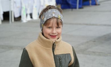 portret uśmiechniętego chłopca w w beżowo- czarnej kurtce na tle placu Stefana Żeromskiego.