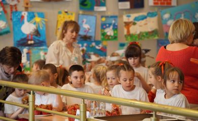 dzieci z przedszkola korzystają z poczęstunku na holu przed salą widowiskową, w tle plakaty z bocianami wykonane przez dzieci z przedszkoli