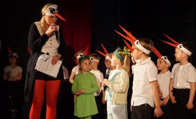 prezentacja przedszkolaków przebranych za bociany na scenie sali widowiskowej, konferansjer przebrany za bociana,