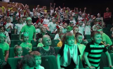 publiczność ogląda występujace dzieci na scenie, głownie są to dzieci przebrane za żabki i bociany