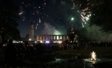 Zgromadzony tłum ogląda pokaz sztucznych ogni nad ruinami zamku.