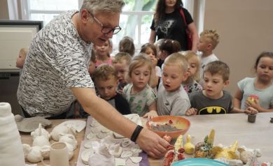 Prowadzący pokazuje dzieciom, wcześniej powstałe prace.